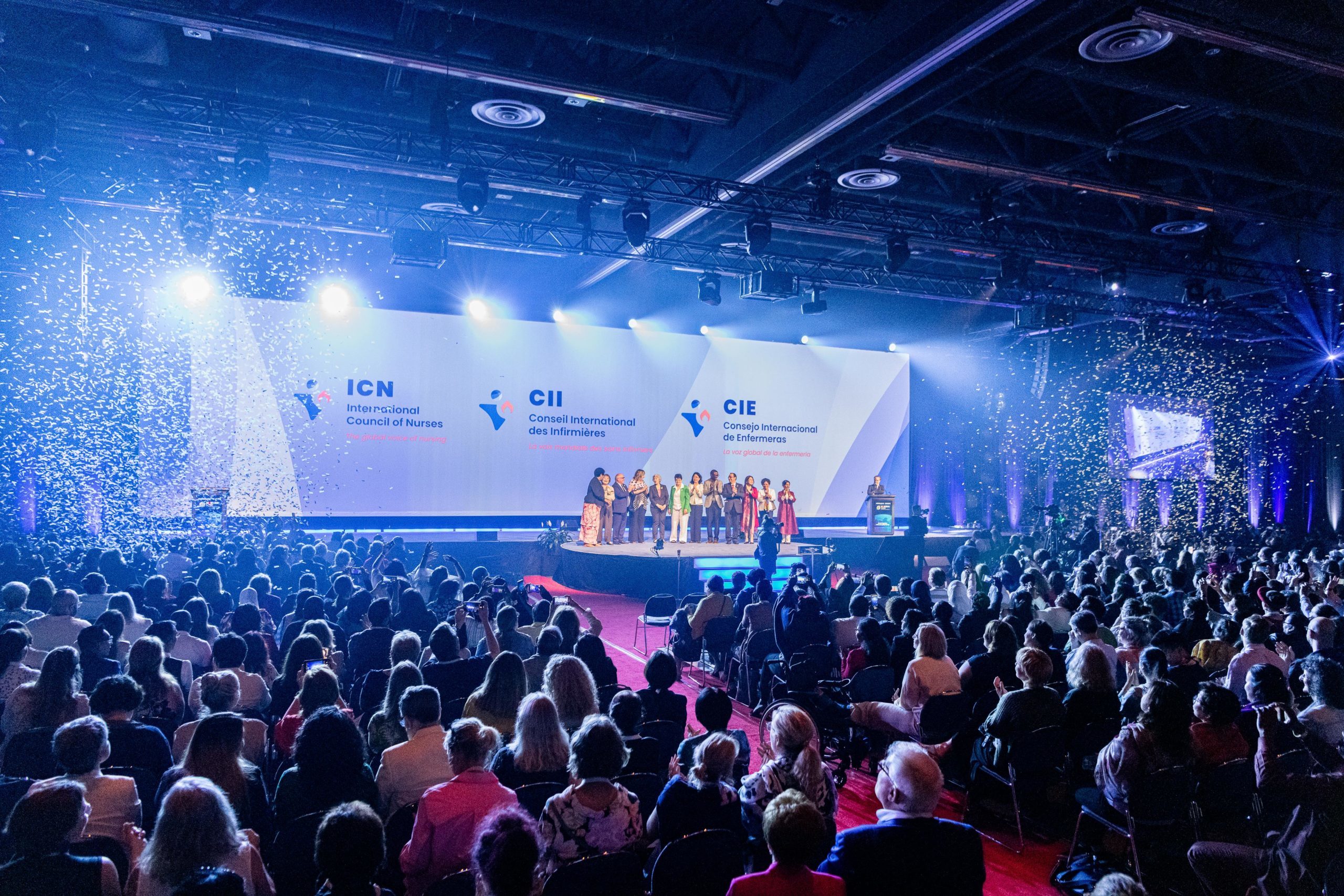 A large audience looks towards an ICN-branded stage with a dark, celebratory atmosphere.